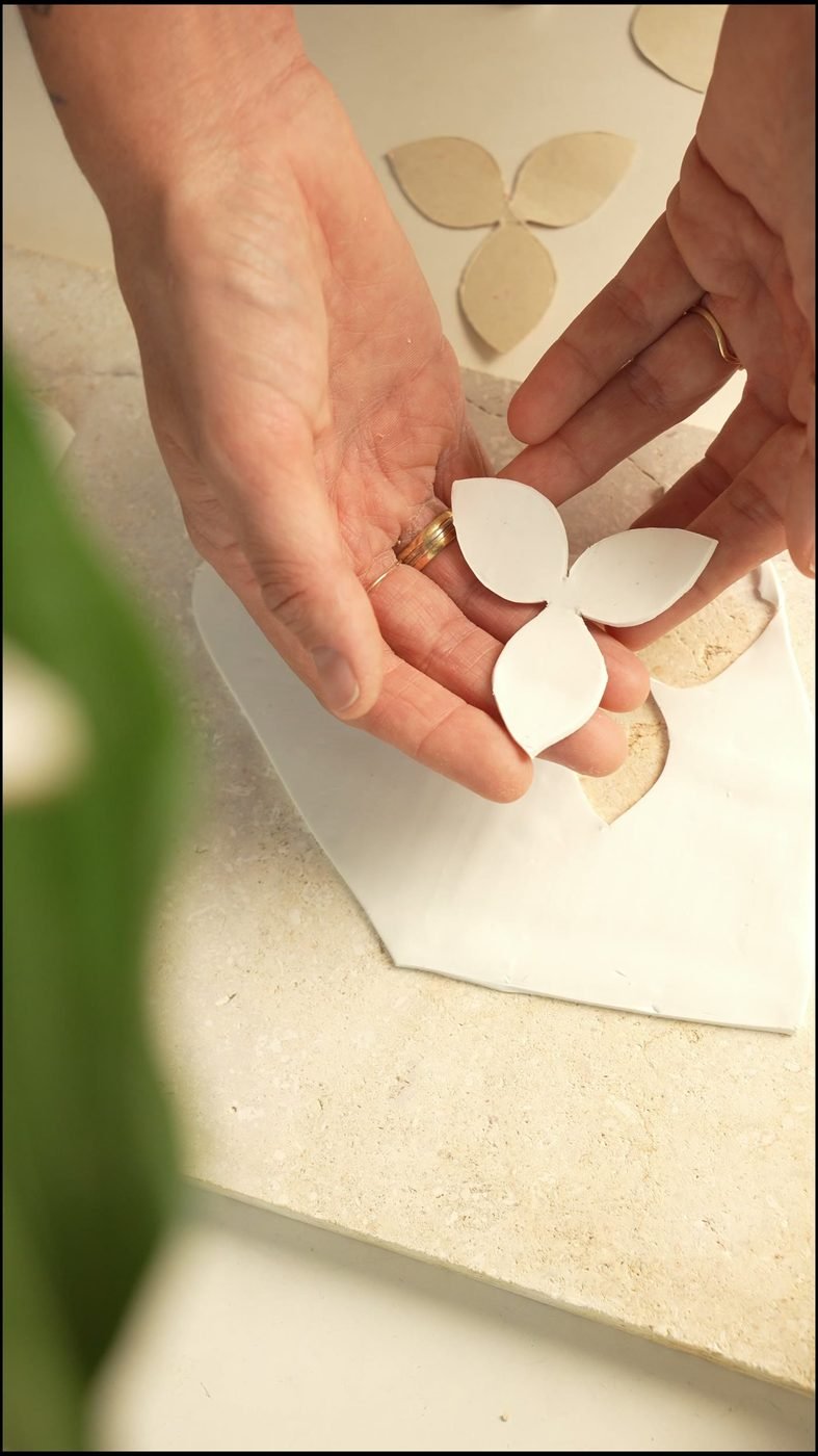 Manos modelando pétalos de arcilla en el taller Menta